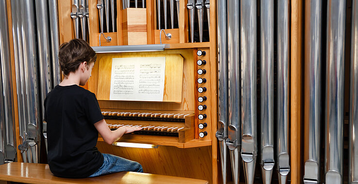 Junge sitzt an Orgel