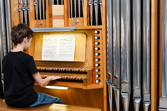 Junge sitzt an Orgel