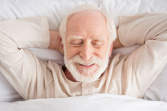 Mann liegt mit Pyjama im Bett