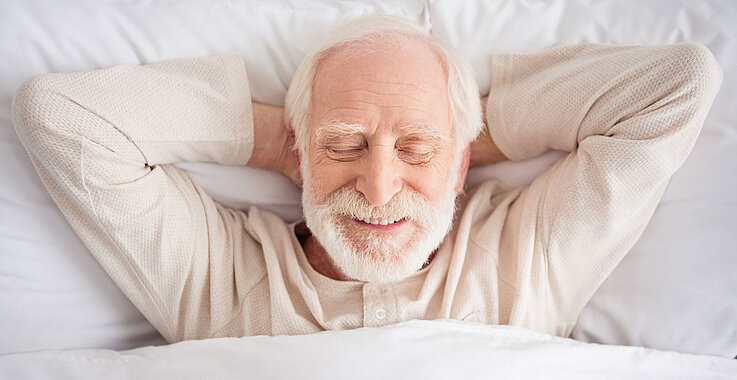 Mann liegt mit Pyjama im Bett