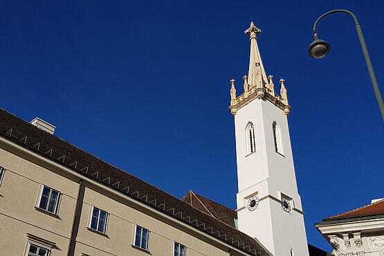 Der weithin sichtbare Kirchturm von Sankt Augustin, im Schatten der Wiener Hofburg.